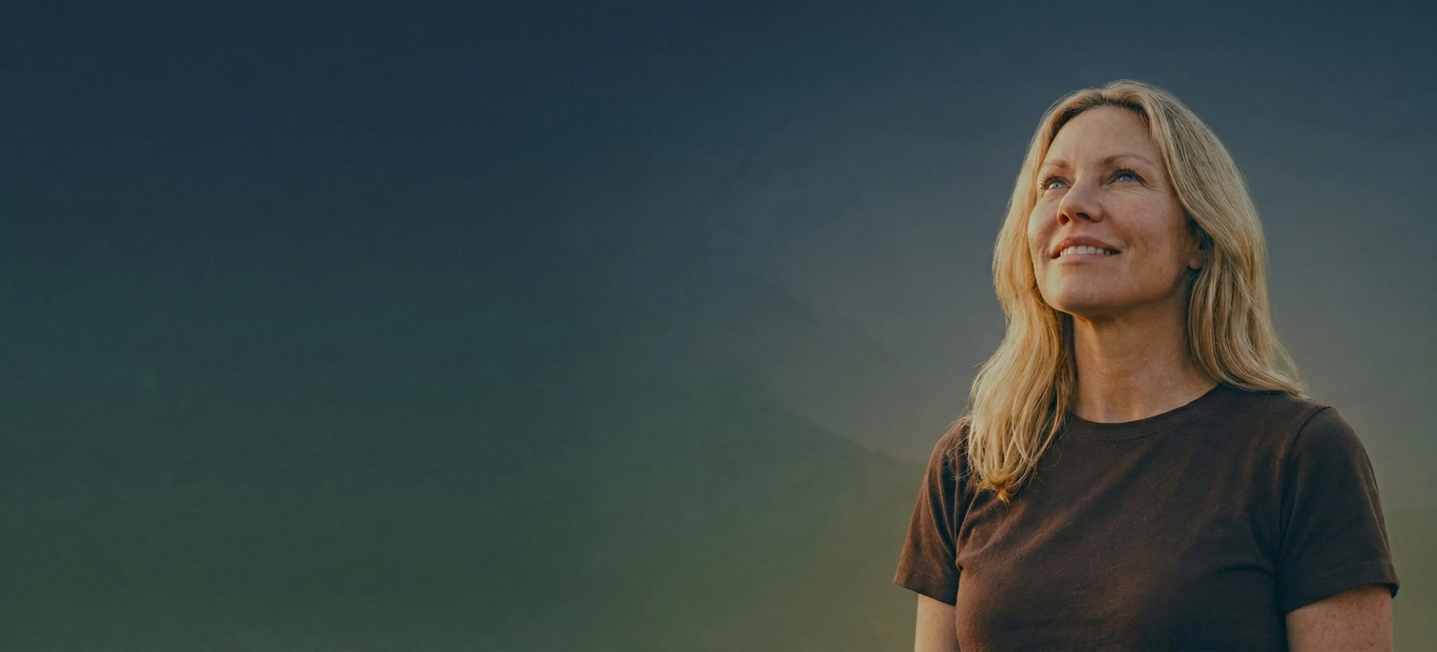 Woman looking up against teal sky